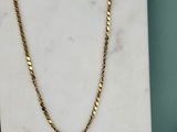 un collier à chaîne en or posé sur une dalle de marbre