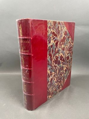 an old book with a red cover sitting on top of a table