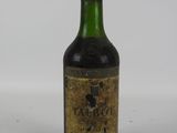 une vieille bouteille de vin posée sur une table blanche