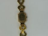 an image of a gold bracelet with a clock on it ' s side