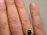 a person ' s hand holding a ring with a black diamond
