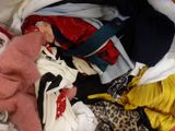a pile of clothes on a bed with a stuffed animal