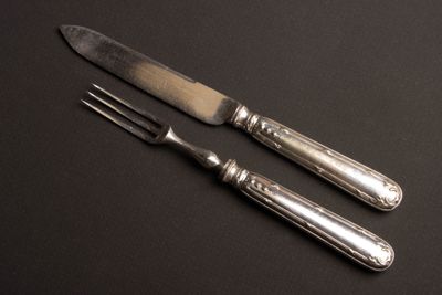 deux fourchettes et un couteau posés sur une table noire