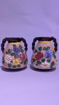 deux vases décorés de fleurs, placés l'un à côté de l'autre