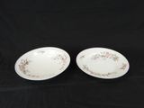 pair of white dishes with pink flowers on them on a black background