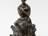 a bronze statue of a woman sitting on a rock