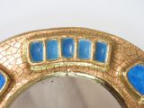 a gold and blue mirror sitting on a table