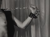 black and white photo of a shirtless man with a chain around his neck