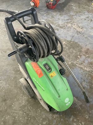 une tondeuse à gazon verte à laquelle est raccordé un tuyau d'arrosage