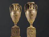 une paire d'urnes antiques en bronze posées sur des socles, sur fond noir