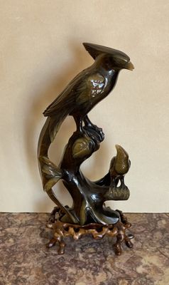 une statue représentant un oiseau sur une branche, sur laquelle est perché un autre oiseau