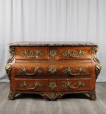 une commode ancienne avec un plateau en marbre, posée sur un parquet