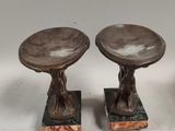 pair of bronze sculptures of a man and a woman on pedestals