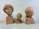 three clay busts of children sitting next to each other