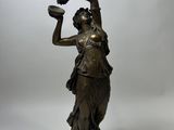 an antique bronze statue of a woman holding a pitcher