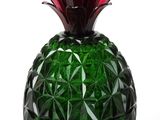 a green glass pineapple with a red flower in it