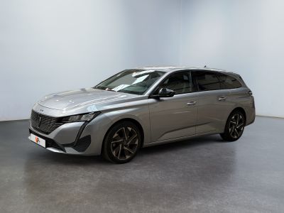 La voiture argentée est garée dans une pièce blanche au sol noir.