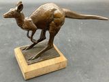 statue of a kangaroo on a wooden base on a gray surface
