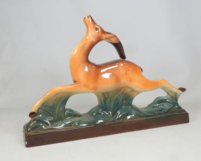 a figurine of a deer that is running in the grass