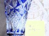 un vase en verre bleu posé sur une table, sur lequel est posée une note