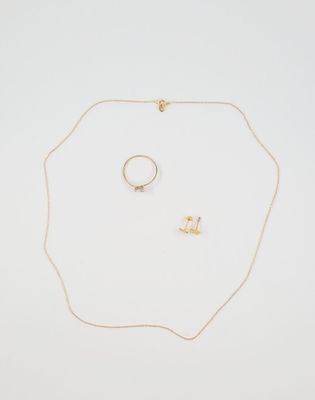 a gold necklace, ring, and earring on a white surface