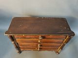a small wooden chest with three drawers on it