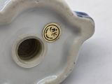a white and blue vase with a gold button on it