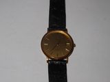 une photo d'une montre en or montée sur un bracelet en cuir noir