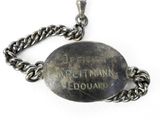 a silver plate with a chain around it on a white surface