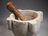 mortar with a wooden stick in it on a gray background