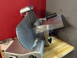 a meat slicer that is sitting on a wooden table