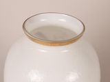 a white vase with a gold rim sitting on a table