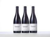 three bottles of red wine are lined up on a table
