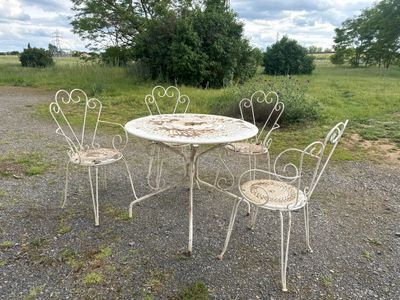 four chairs and a table in the middle of a gravel road