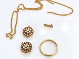un gros plan d'un collier, d'une bague et d'une boucle d'oreille posés sur une surface blanche