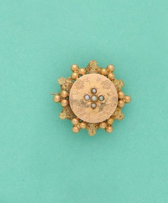 un gros plan d'une broche en or et perles sur fond turquoise
