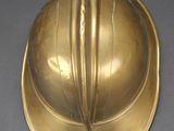 brass plated fireman ' s helmet on a gray surface