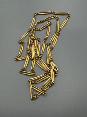 un gros plan d'un collier plaqué or posé sur une surface grise