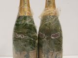 two bottles of champagne are wrapped in plastic and sitting on a table