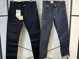 deux paires de jeans suspendues à un portant dans un magasin de vêtements