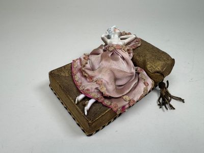 a small doll sitting on top of an old book