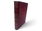 un vieux livre à la couverture rouge posé sur une surface blanche