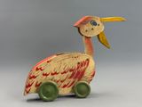 a wooden bird that is sitting on top of a toy car