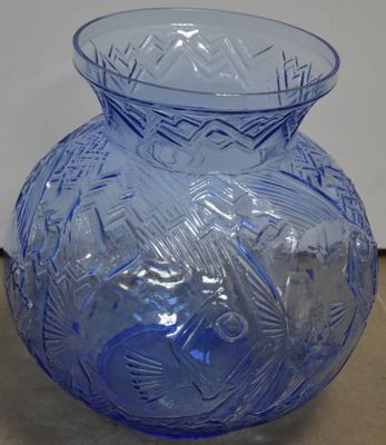un vase en verre bleu posé sur un mur, à côté d'un mur blanc