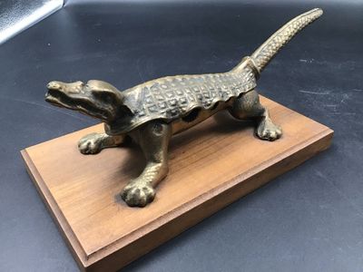 figurine en bronze représentant un lézard, posée sur un socle en bois