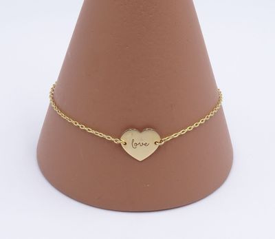 Le bracelet en forme de cœur doré est posé sur un cône marron muni d'une chaîne dorée