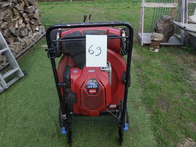 une tondeuse à gazon rouge posée sur l'herbe dans le jardin