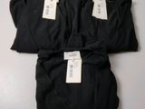 three black shirts with tags on them sitting on a table