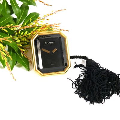 a black and gold watch with a tassel on a table