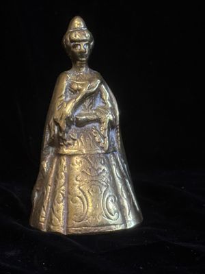 une cloche ancienne en laiton représentant une femme tenant un bébé dans ses bras